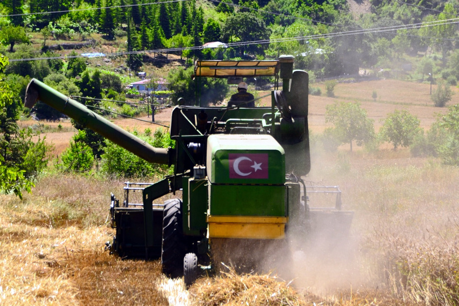 Combine harvester working in a dusty field under demanding agricultural operating conditions.