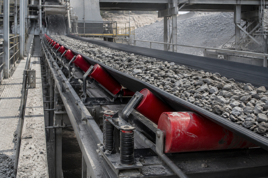 Troughing conveyor idlers supporting a loaded belt carrying crushed stone in a quarry