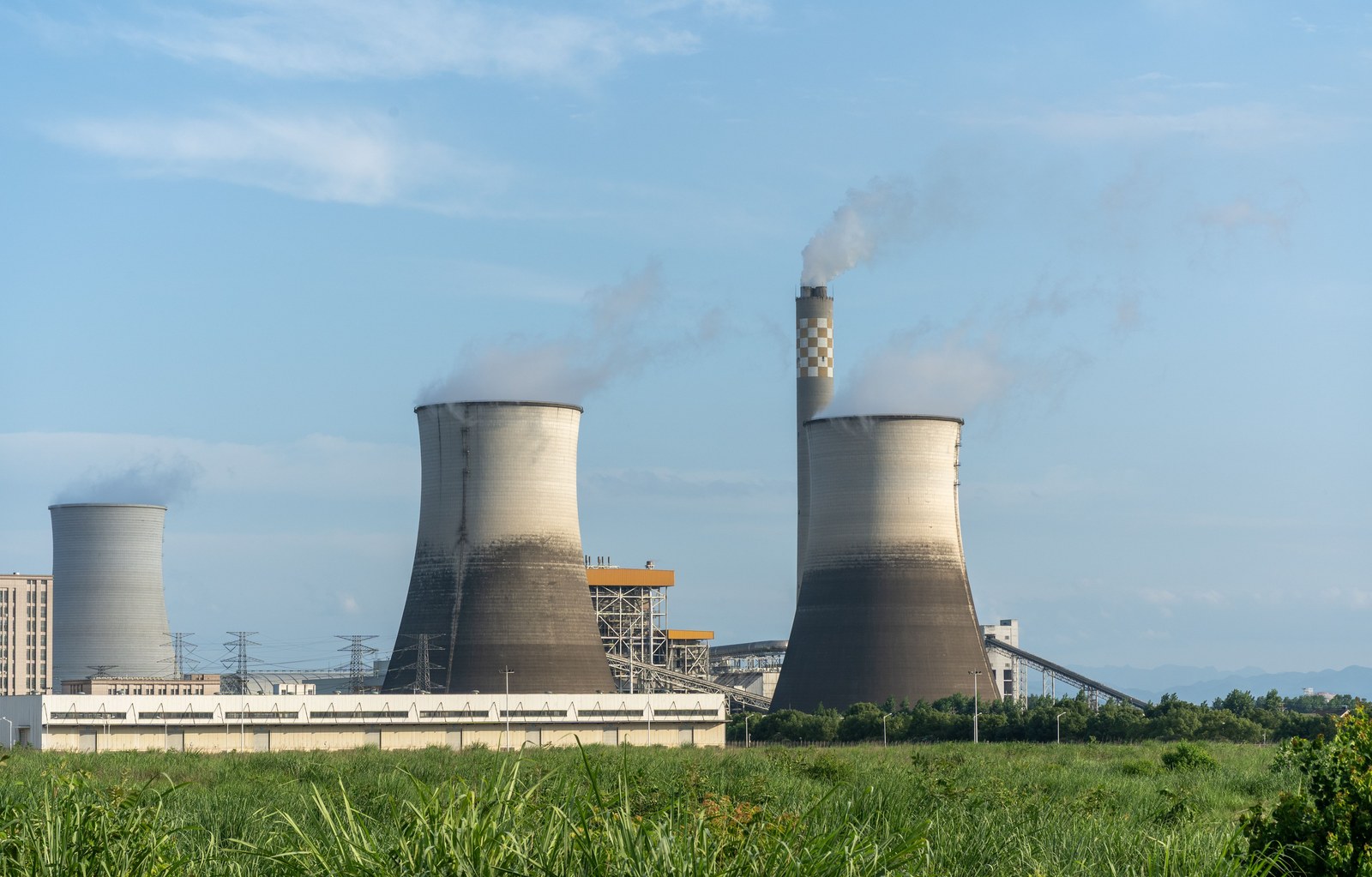 industrial power plant with cooling towers and stacks in a green landscape