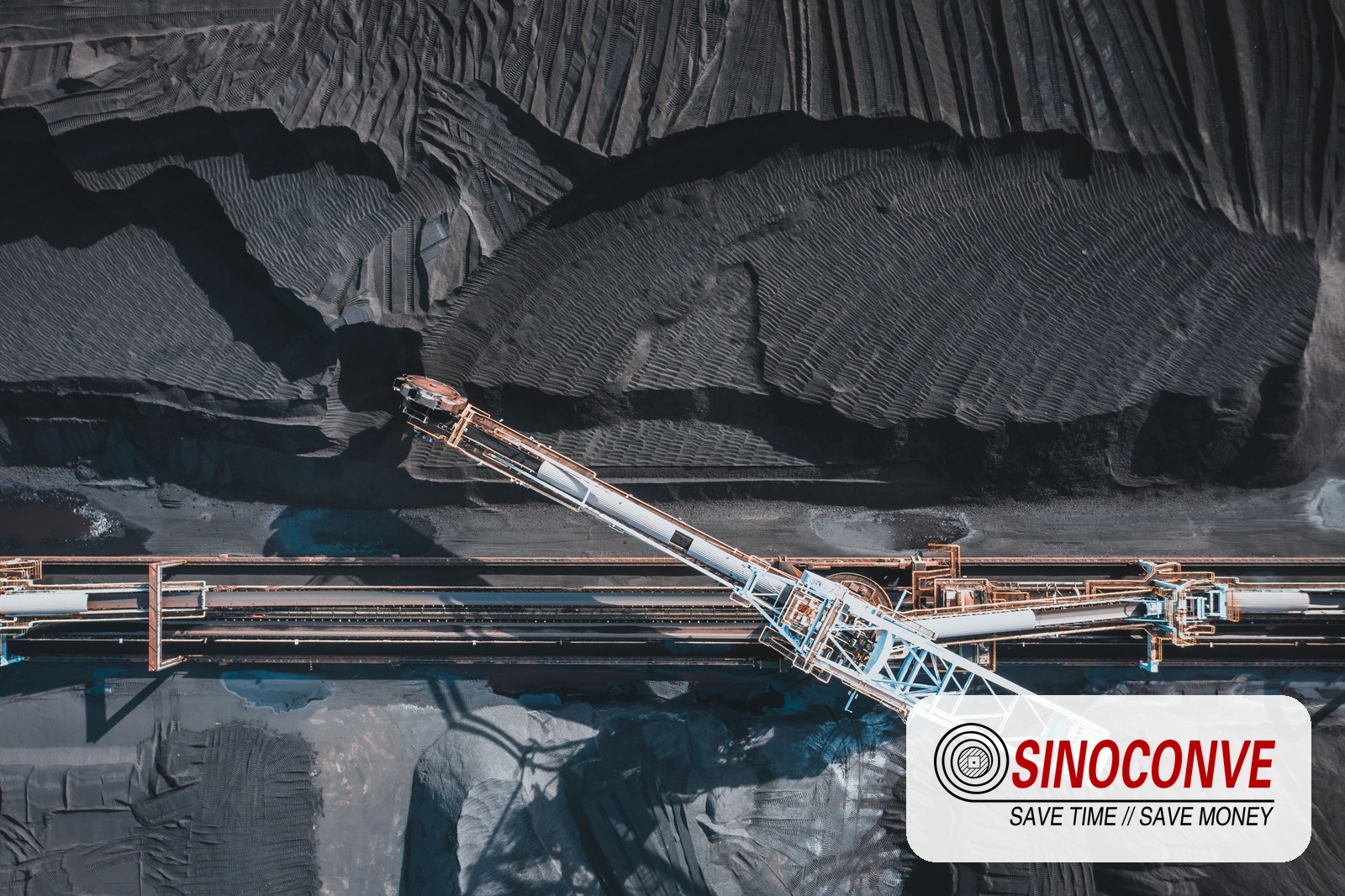 Fabric conveyor belt running on a stacker conveyor at a quarry stockpile with aggregate material and dust