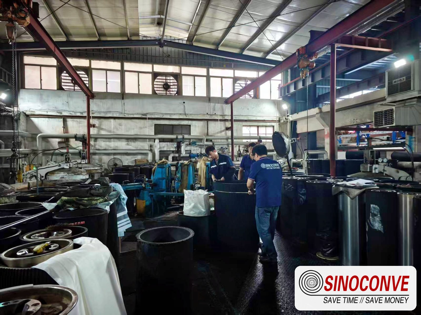 Workers operating the press area of a conveyor belt factory where biomass belt covers are built