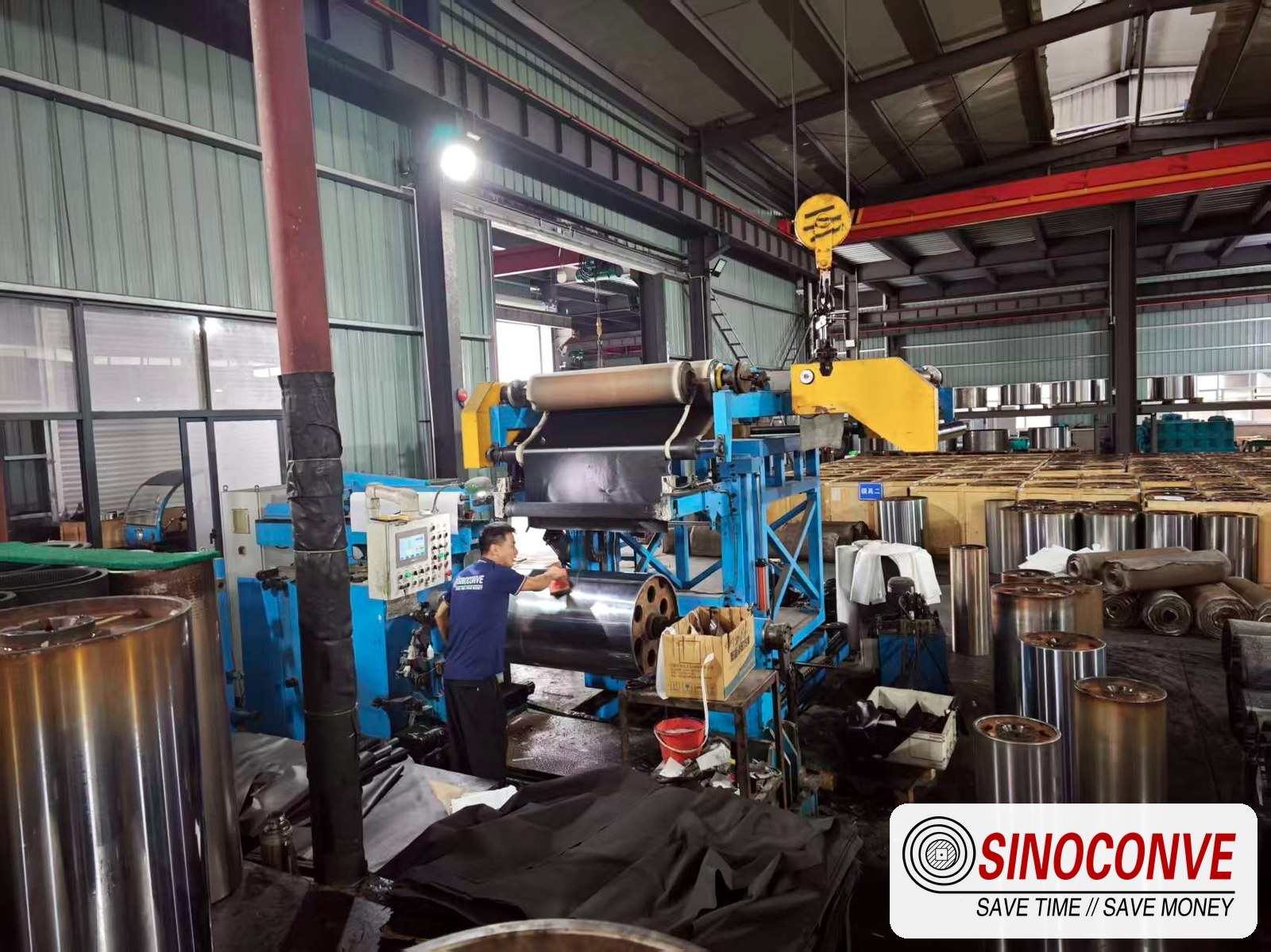 Workers checking a wood panel conveyor belt beside blue production equipment in the SINOCONVE factory